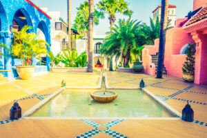 Colorful courtyard with a central fountain and palm trees.